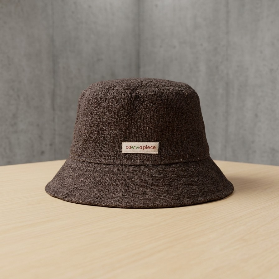 Brown bucket hat with a brand label on a beige surface and gray background